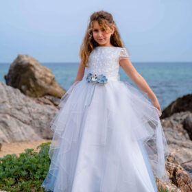 vestido de comunión Co & Ce en tul celeste con cuerpo bordado y flores en la cintura