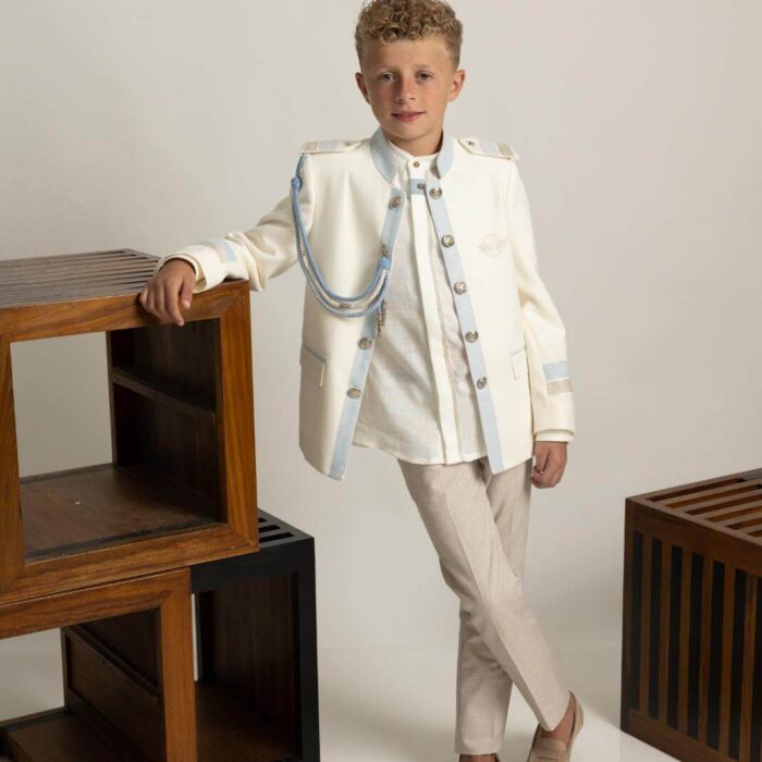 Traje de Comunión almirante Amalio Rubio con chaqueta beige de cuello Mao, adornos celestes, camisa con vivos en la abotonadura y pantalón celeste.