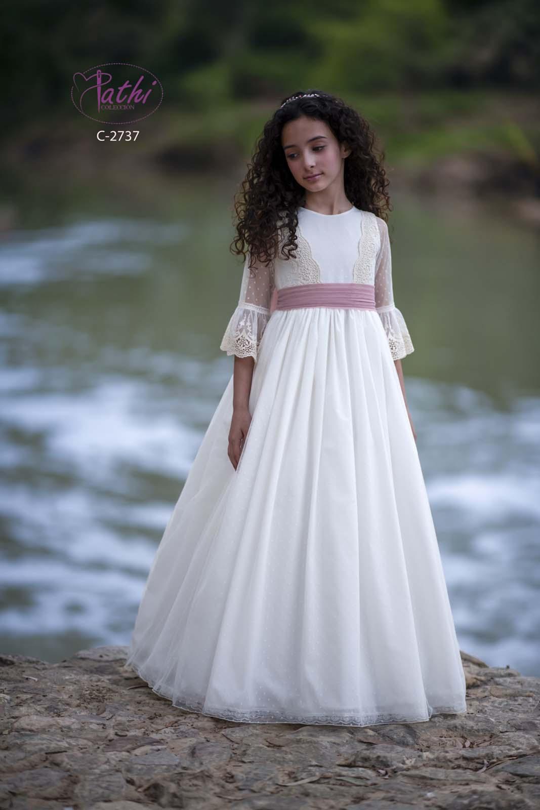 Vestido de comunión Pathi Colección con falda de tul, cuerpo de encaje y lazada rosa nude.